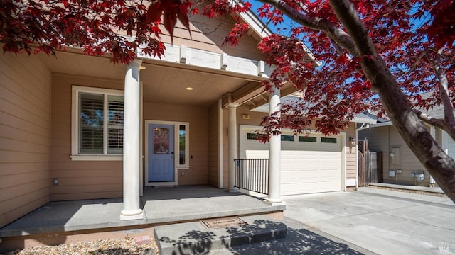 view of exterior entry featuring a porch, driveway, and a garage