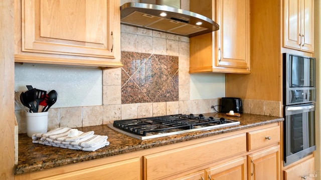kitchen with light brown cabinets, extractor fan, dark stone counters, stainless steel appliances, and tasteful backsplash