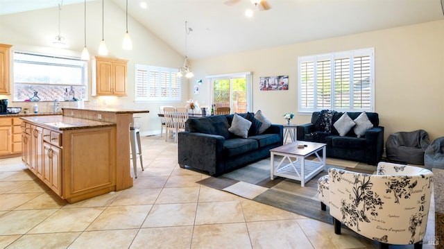 living area with light tile patterned floors, high vaulted ceiling, baseboards, and a notable chandelier