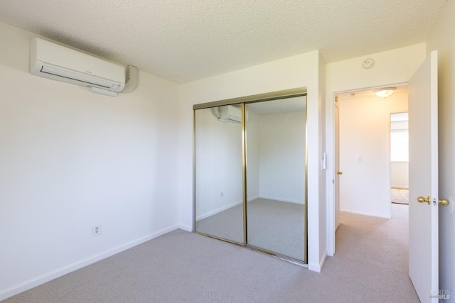 unfurnished bedroom featuring a wall mounted AC, carpet, a closet, and a textured ceiling