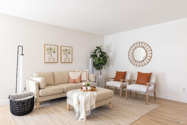living room featuring light wood-style flooring, a textured ceiling, and baseboards