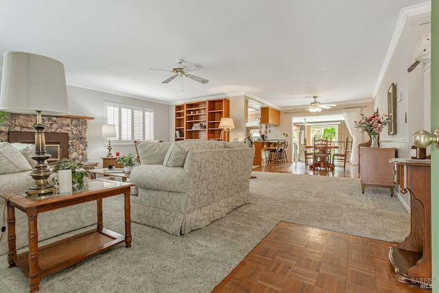 living room featuring crown molding, a ceiling fan, and a stone fireplace