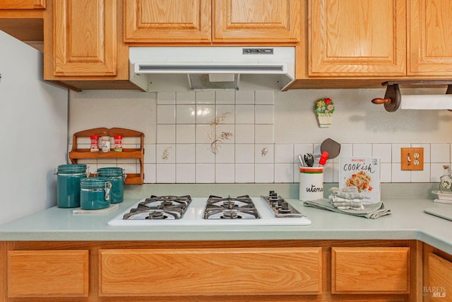 kitchen with under cabinet range hood, decorative backsplash, light countertops, and white gas stovetop
