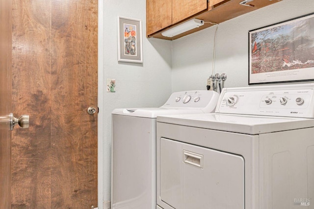 laundry area with washing machine and clothes dryer and cabinet space