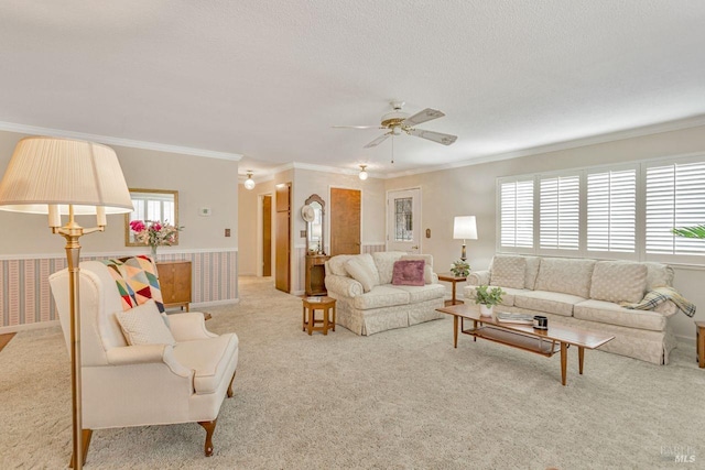 living room featuring a textured ceiling, a ceiling fan, crown molding, and carpet floors