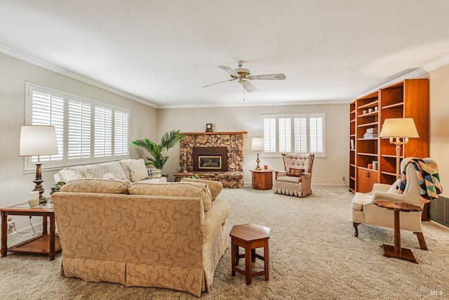 carpeted living area featuring a stone fireplace, baseboards, crown molding, and ceiling fan