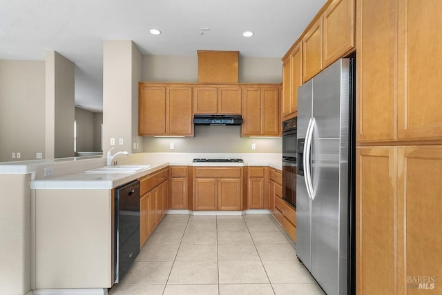 kitchen featuring light tile patterned floors, a sink, a peninsula, under cabinet range hood, and black appliances