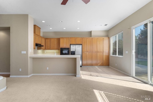 kitchen featuring stainless steel fridge, light countertops, under cabinet range hood, black oven, and light colored carpet
