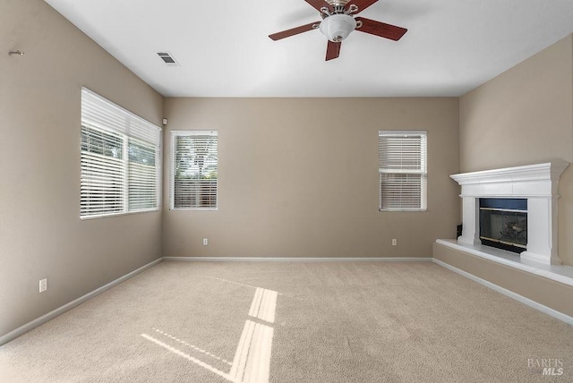 unfurnished living room with carpet, visible vents, baseboards, and ceiling fan