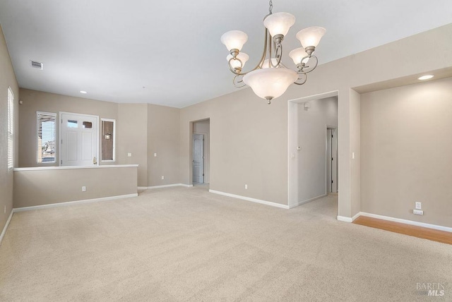 empty room featuring a chandelier, light carpet, baseboards, and visible vents