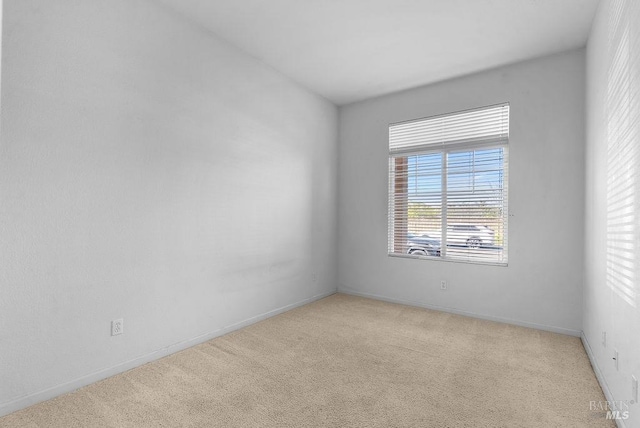 carpeted spare room featuring baseboards