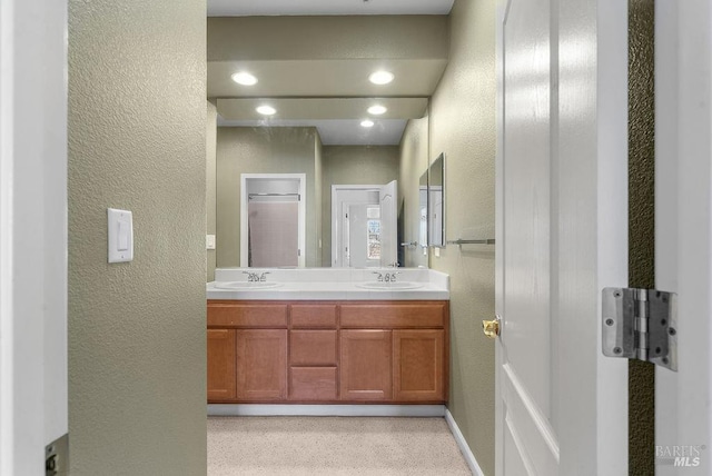 bathroom with double vanity, a textured wall, and a sink