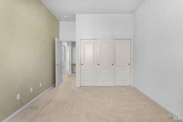 unfurnished bedroom with carpet flooring, a closet, and baseboards