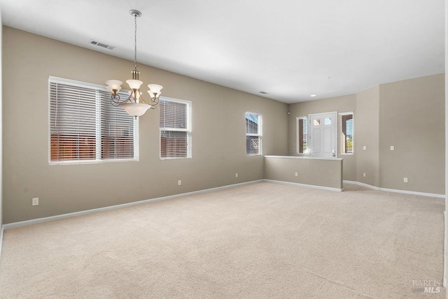spare room with visible vents, baseboards, an inviting chandelier, and light carpet
