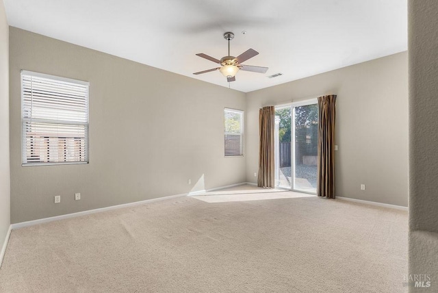 carpeted spare room with baseboards, a ceiling fan, and visible vents