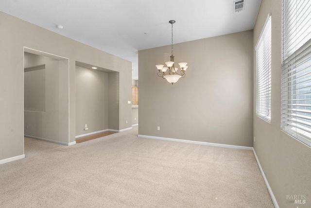 spare room featuring a chandelier, visible vents, baseboards, and carpet floors