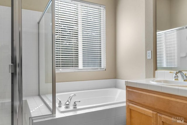 full bathroom featuring a shower stall, a garden tub, and vanity