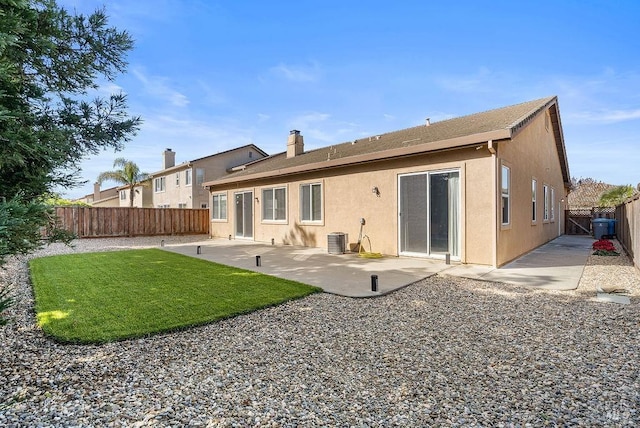 back of house with central AC unit, a yard, a fenced backyard, a patio, and stucco siding