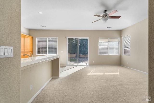 unfurnished room with light carpet, baseboards, and a ceiling fan