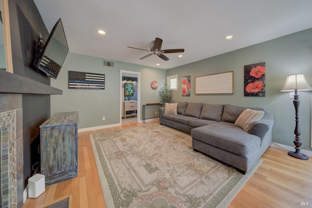 living area with visible vents, baseboards, a ceiling fan, a fireplace, and wood finished floors