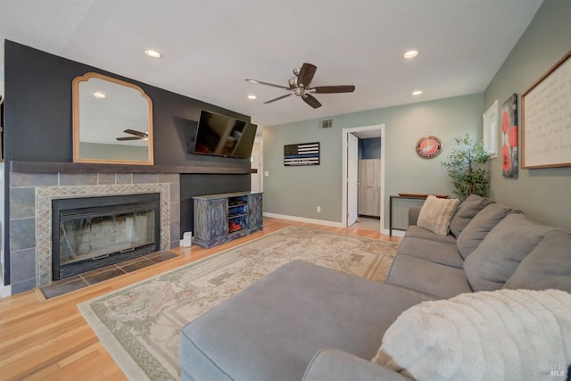 living area featuring wood finished floors, a fireplace, a ceiling fan, and visible vents