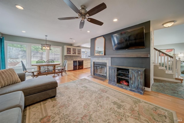 living room with light wood-style flooring, a ceiling fan, stairway, and a fireplace with flush hearth
