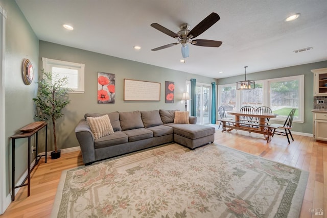 living area featuring visible vents, ceiling fan, light wood-style floors, and baseboards
