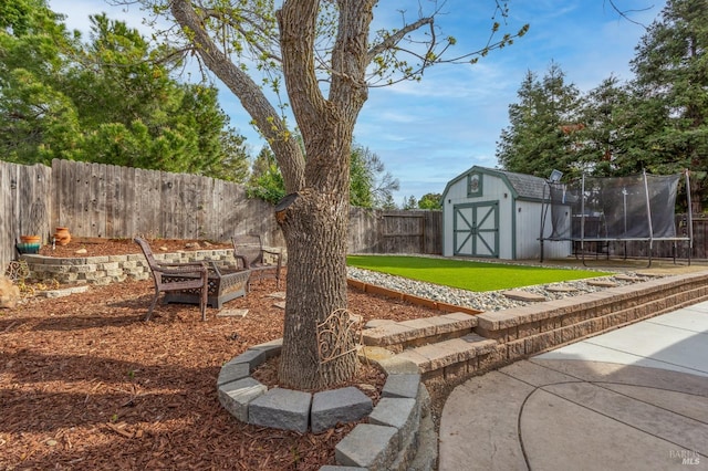 view of yard with a shed, a fenced backyard, an outdoor structure, a patio, and a trampoline
