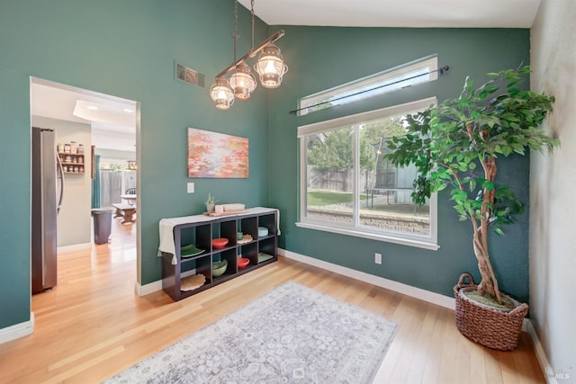 sitting room featuring visible vents, baseboards, high vaulted ceiling, and wood finished floors