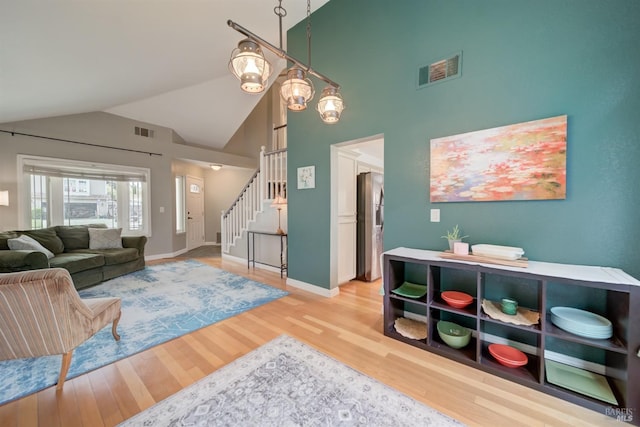 living area with light wood-style floors, baseboards, visible vents, and stairs