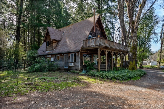view of front facade featuring dirt driveway, a wooden deck, and cooling unit