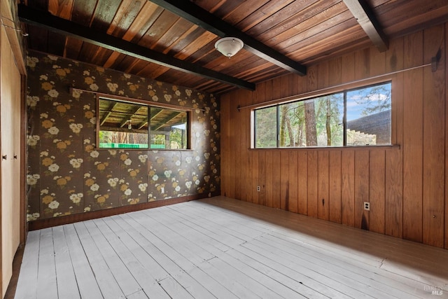 unfurnished room with baseboards, wood ceiling, wood-type flooring, and beam ceiling