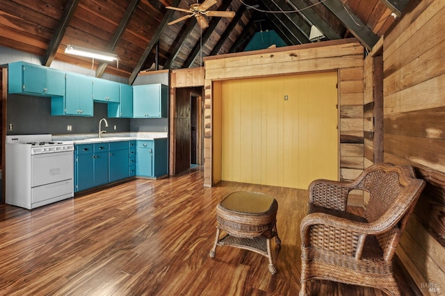 kitchen featuring white gas stove, beam ceiling, wooden walls, wood finished floors, and blue cabinetry