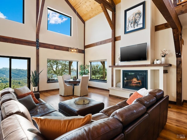 living area featuring wood finished floors, high vaulted ceiling, and baseboards