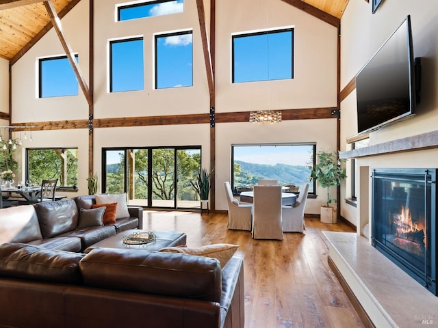 living area with high vaulted ceiling, a high end fireplace, wood-type flooring, and wooden ceiling