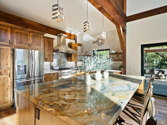 kitchen featuring wall chimney range hood, stone countertops, a large island, wood finished floors, and stainless steel appliances