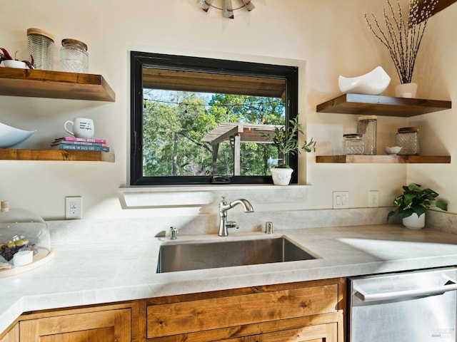 kitchen with light countertops, stainless steel dishwasher, a sink, and open shelves