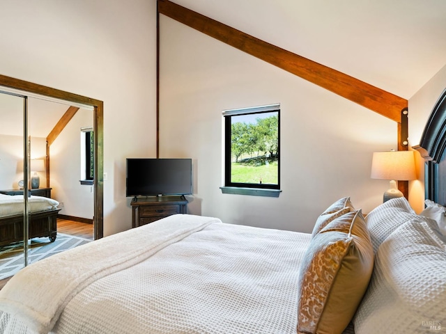bedroom with baseboards, wood finished floors, and lofted ceiling