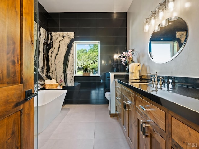 bathroom with a freestanding bath, tile patterned floors, vanity, and toilet
