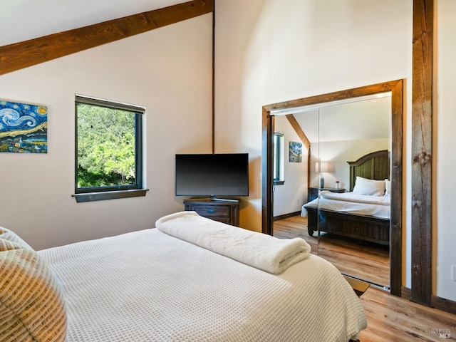bedroom featuring light wood finished floors and lofted ceiling with beams