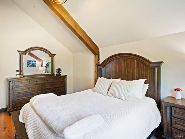 bedroom with vaulted ceiling with beams and wood finished floors