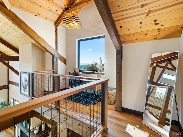 hall featuring plenty of natural light, an upstairs landing, wood ceiling, and beamed ceiling