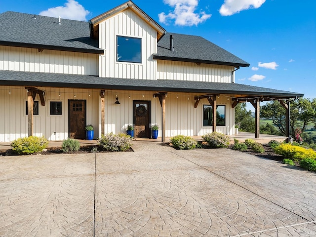 back of property featuring a porch, a shingled roof, and curved driveway