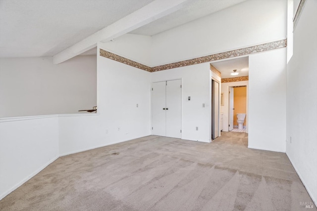 empty room featuring carpet flooring and beamed ceiling