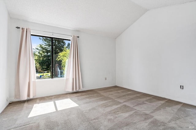 carpeted empty room featuring vaulted ceiling and a textured ceiling