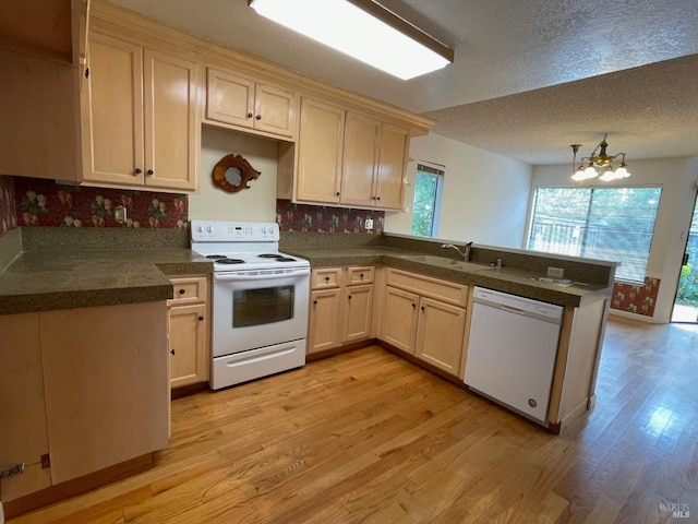 kitchen featuring a peninsula, dishwasher, a sink, and light wood-style flooring