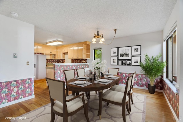 dining area with light wood finished floors, an inviting chandelier, baseboards, and a textured ceiling