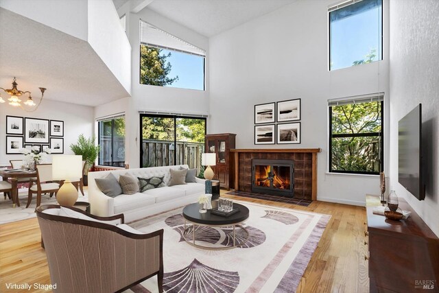 living area featuring plenty of natural light, wood finished floors, a high ceiling, and a tile fireplace