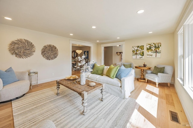 living room featuring visible vents, light wood finished floors, a chandelier, and recessed lighting