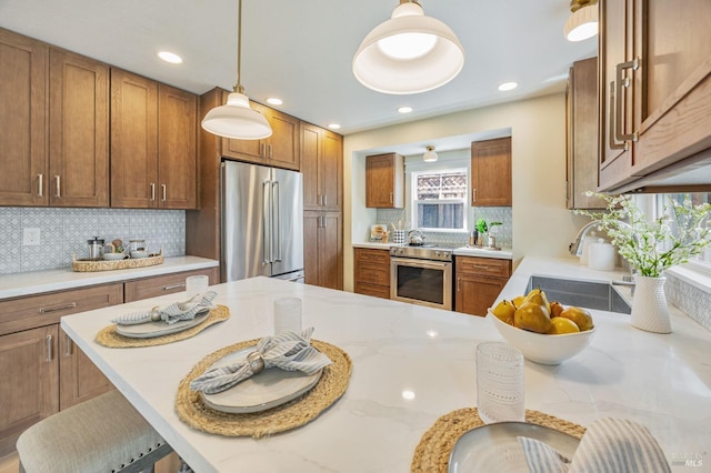kitchen featuring a sink, brown cabinetry, appliances with stainless steel finishes, and a kitchen bar